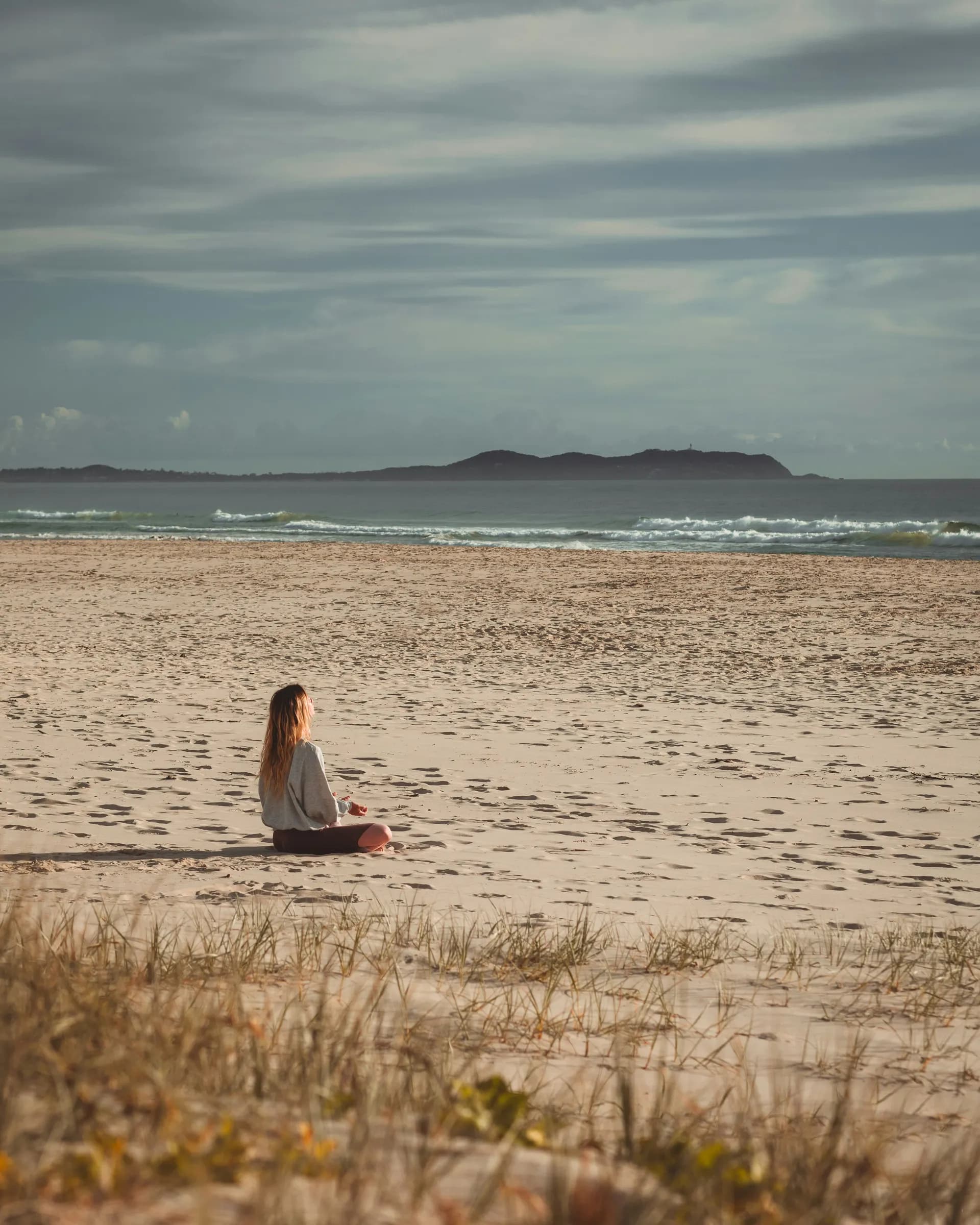 Una mujer meditando en la playa