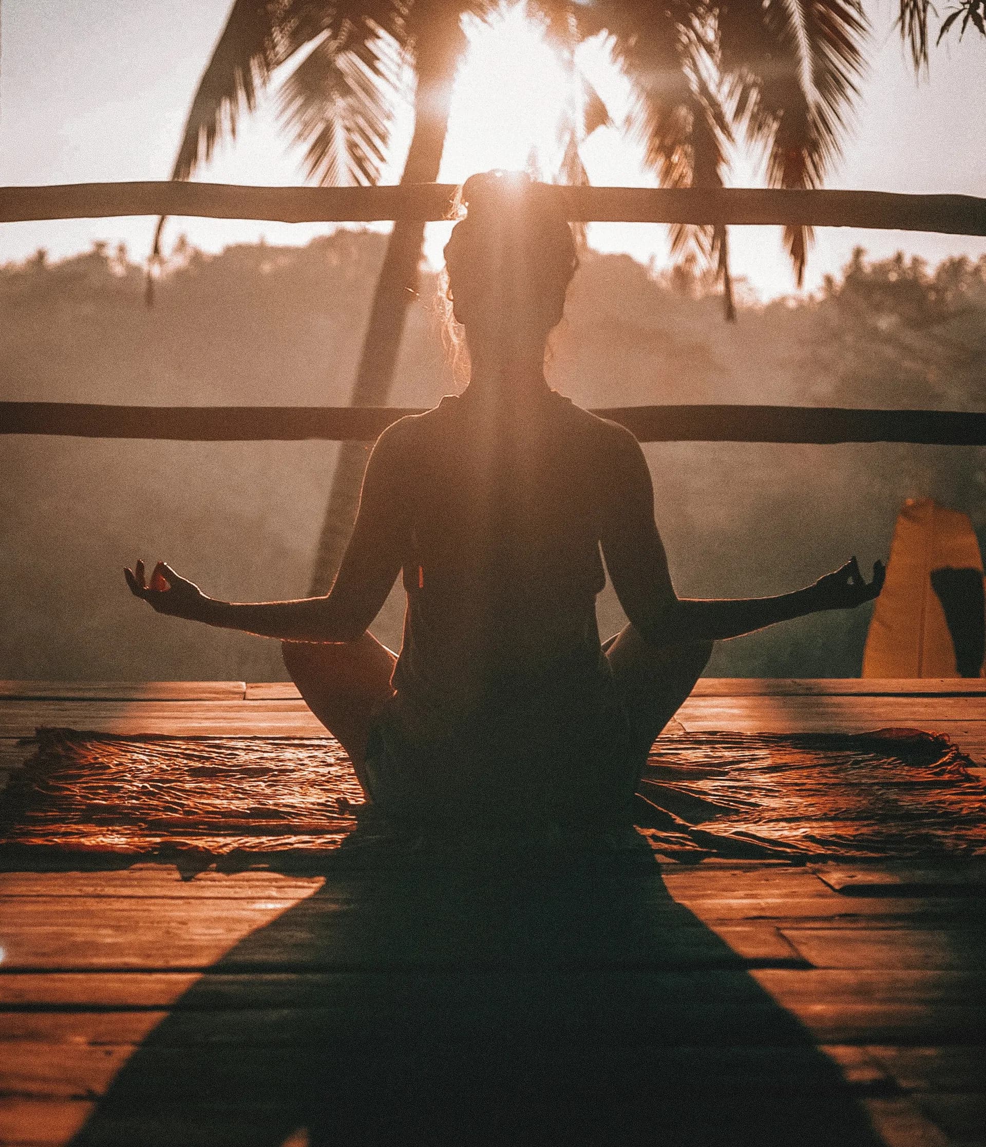 Una mujer meditando frente al sol