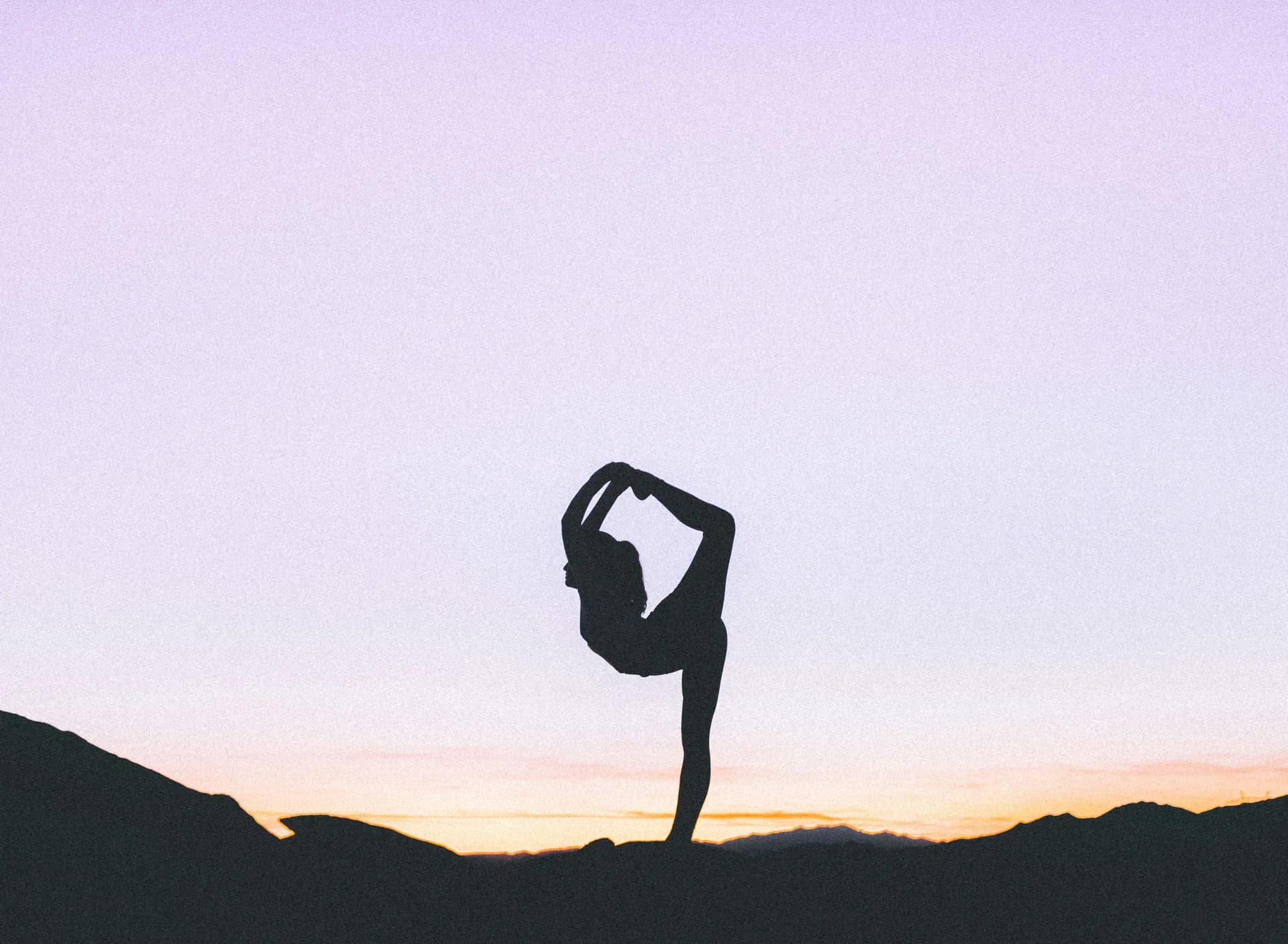 Mujer haciendo yoga en el monte al atardecer