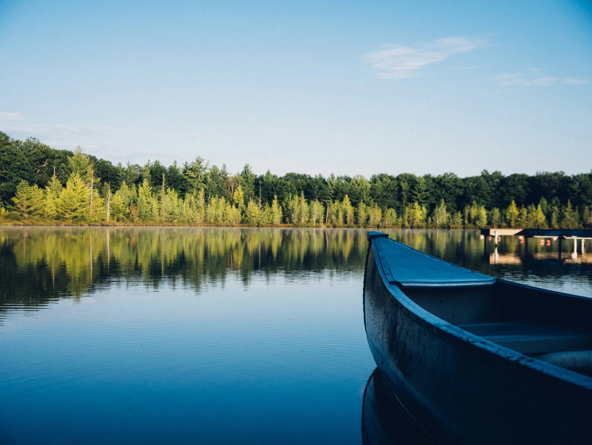 Un lago en calma con una canoa a la derecha