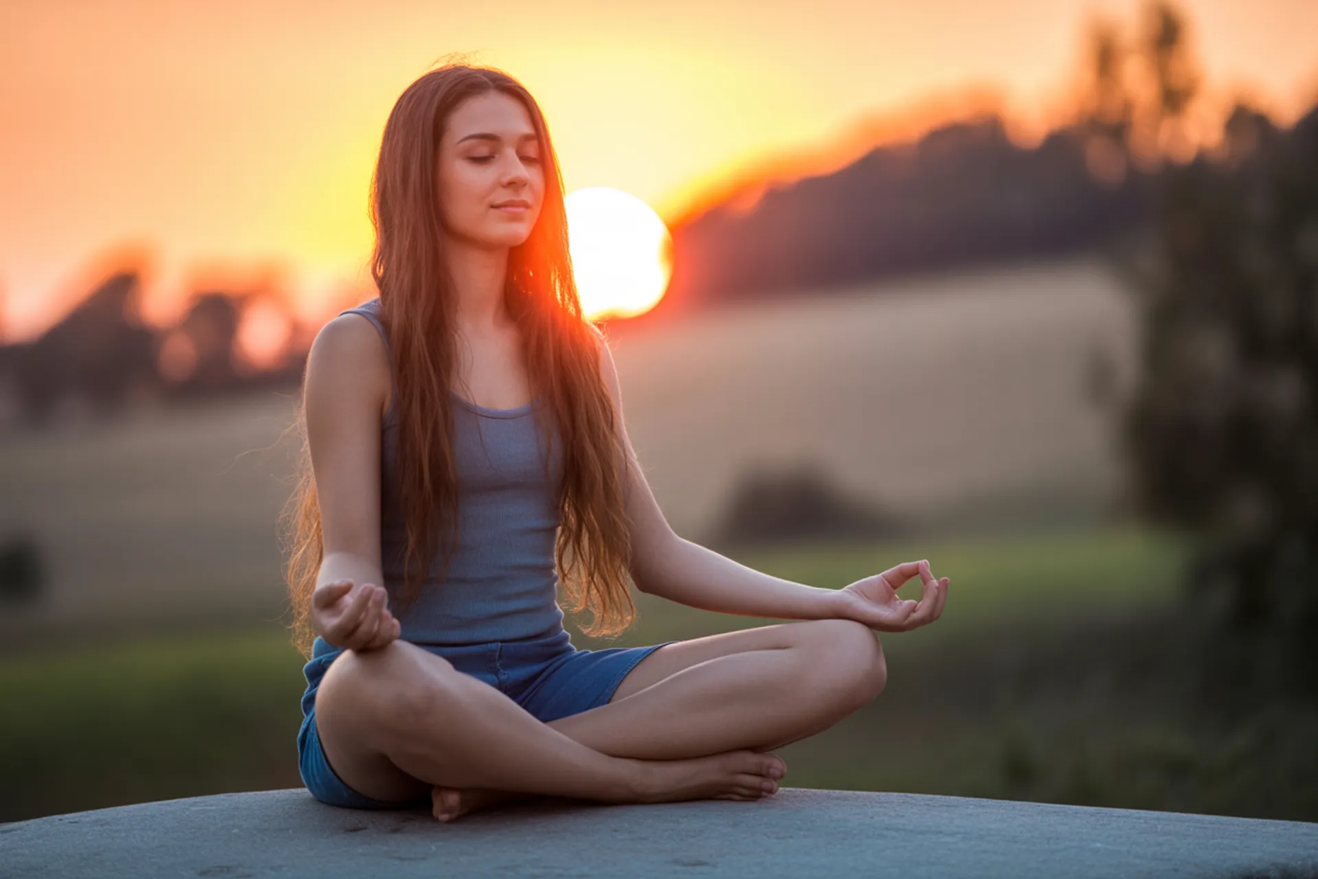 Persona meditando en la naturaleza durante el atardecer