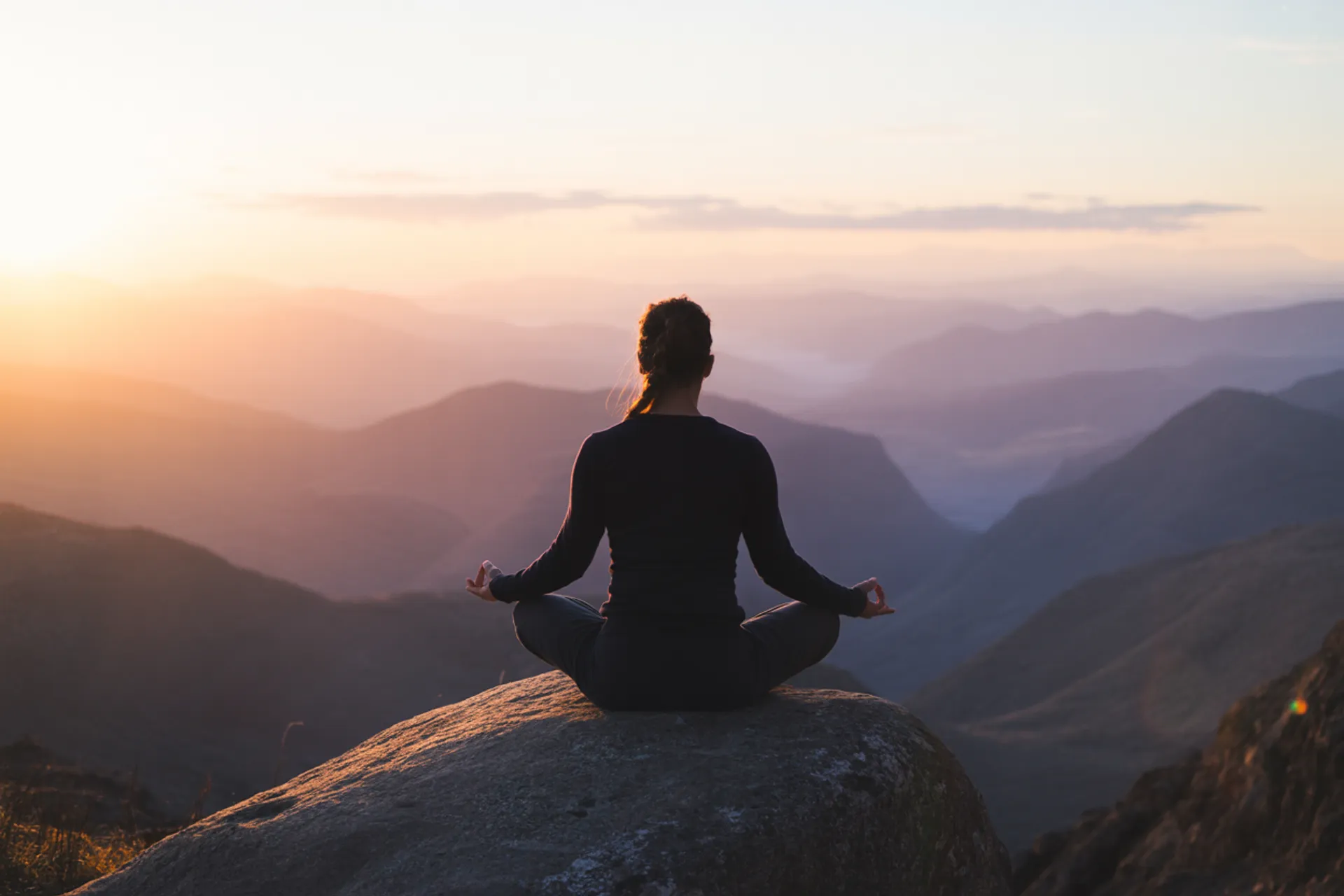 Persona meditando al amanecer en la naturaleza, simbolizando el desapego y la paz interior