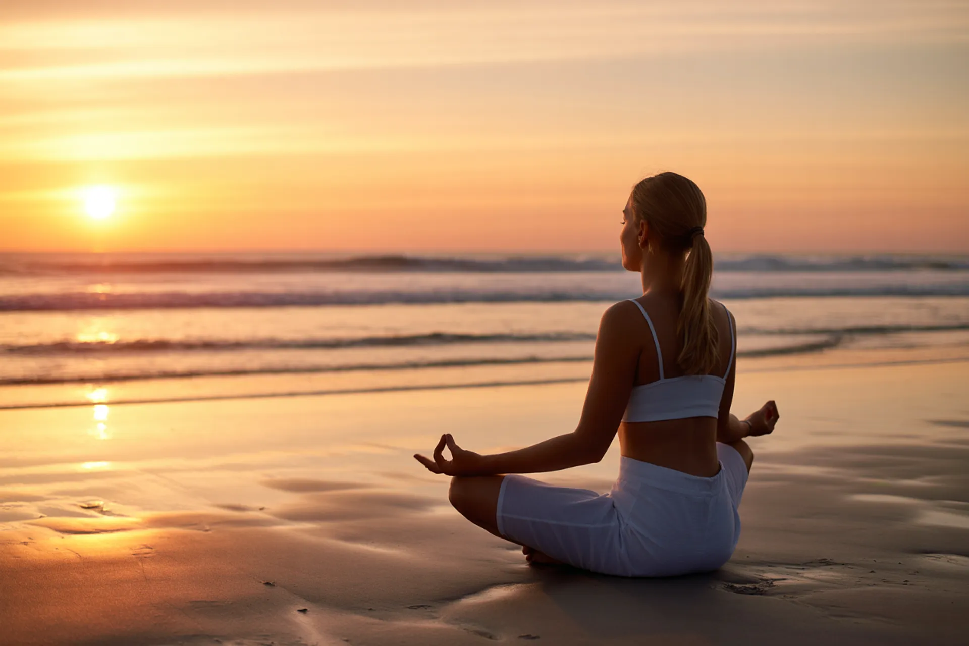 Persona meditando al amanecer en la playa