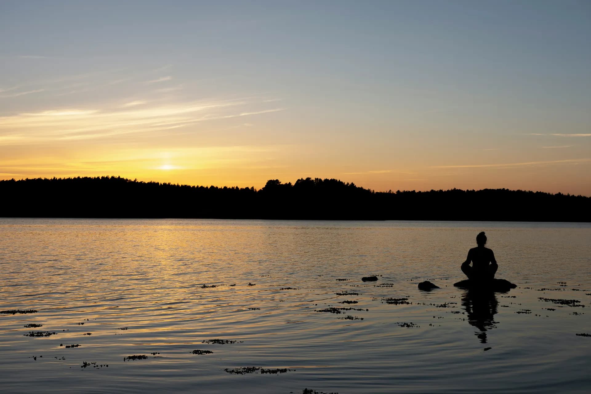 Persona meditando en un lago en el atardecer