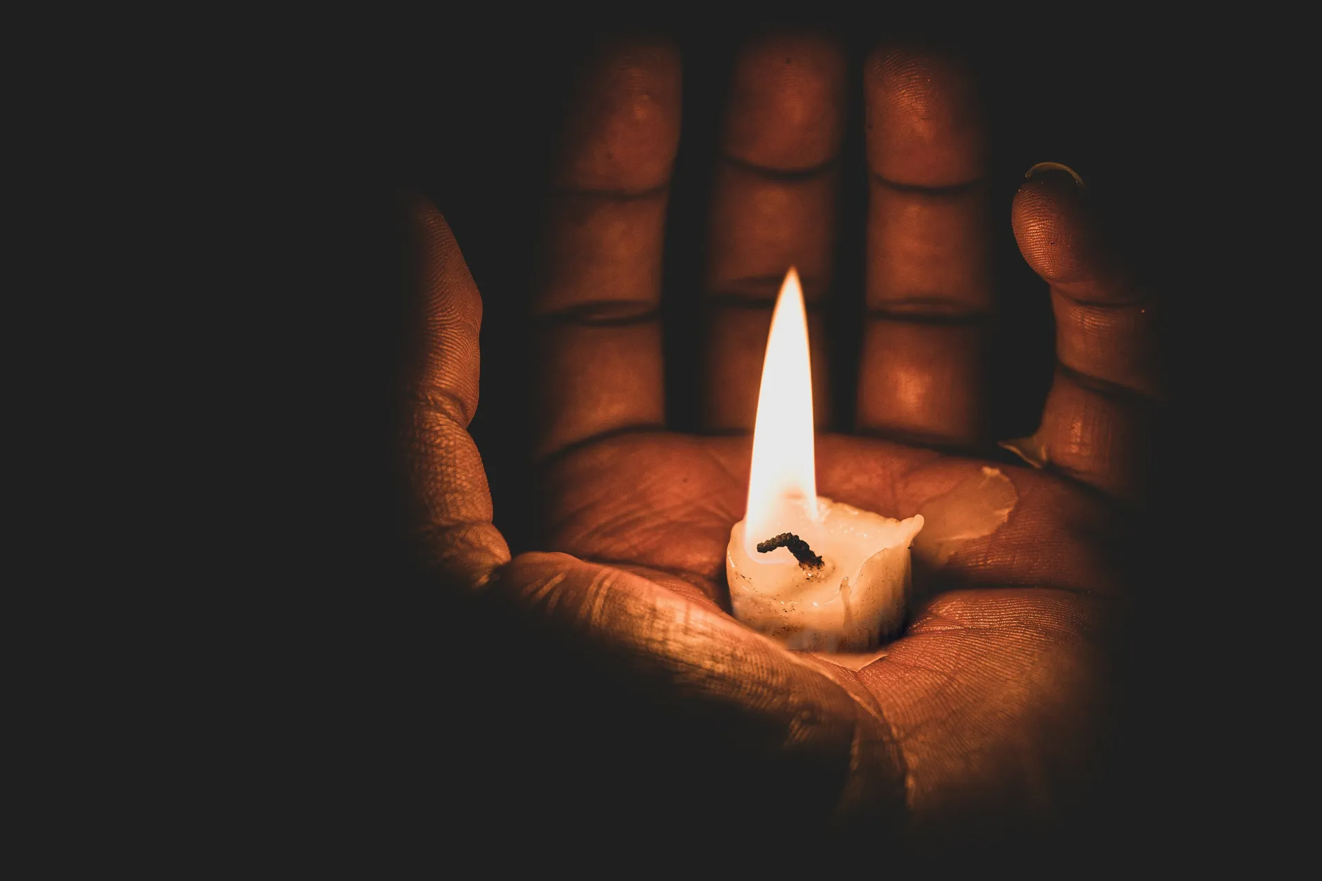 Una mano con una vela en la oscuridad